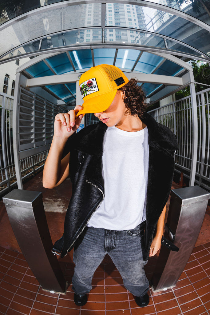 Woman streetwear black jacket leather and yellow trucker hat